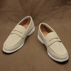 Primo piano di mocassini in pelle scamosciata beige con cuciture su sfondo marrone