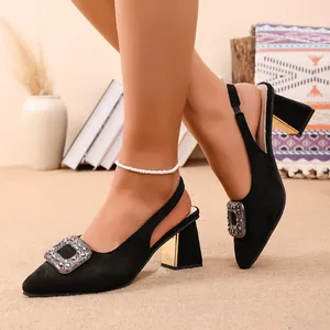 Gros plan sur des escarpins noirs en daim avec boucle en strass et talon carré doré