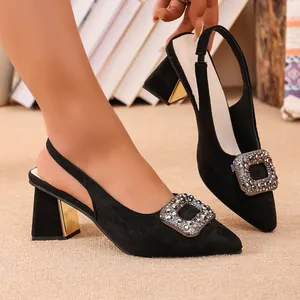Gros plan d'escarpins en daim noir avec boucle en strass étincelante et talon épais.