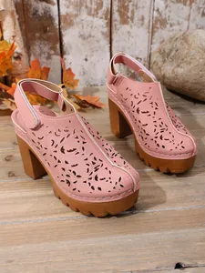 Dettaglio del motivo floreale traforato al laser sui sabot vintage rosa con zeppa.