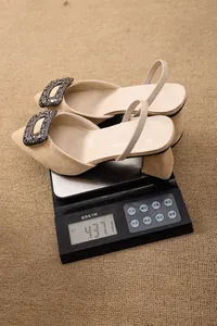 Vue détaillée des sandales en daim beige à talons épais pesées sur une balance numérique