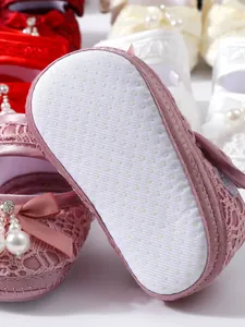 Makro-Detail der weichen Anti-Rutsch-Sohle an rosa Spitzen-Babyschuhen für Neugeborene