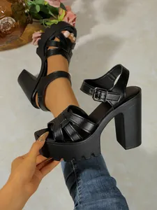 Close-up of black platform block heel Roman sandals with cross strap and buckle closure