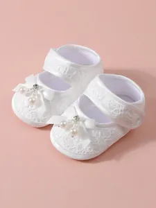 Detailed view of white lace infant baby princess shoes with ribbon bow and pearl accents