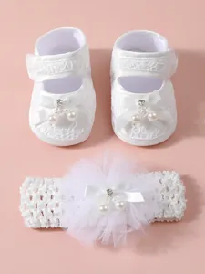 Detailansicht eleganter weißer Babyschuhe aus Spitze mit passendem Blumenstirnband-Set