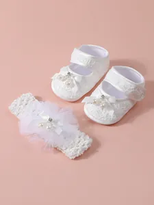 Elegantes Set aus weißen Spitzenschuhen und dazu passendem Blumenstirnband für Babys