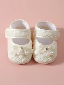 Elegant cream lace baby princess shoes featuring silk ribbon bow and pearl detail