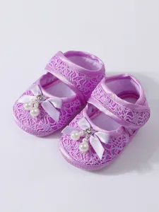 Detail of purple lace baby princess shoes featuring elegant pearls and bows decorations