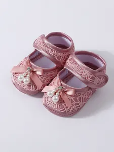 Detailed view of pink lace baby girl princess shoes with bow and pearl accents