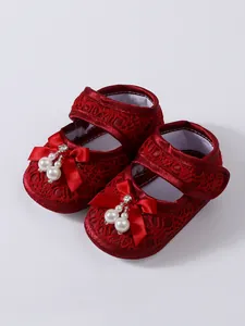 Detail view of red lace baby princess shoes with pearl and bow accents for infants.