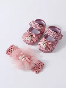 Detailansicht der rosa Baby-Spitzenschuhe und des passenden Perlen-Stirnbands