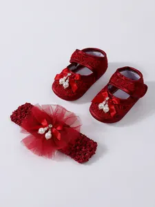 Detaillierte Nahaufnahme von roten Spitzen-Babyschuhen und passendem Blumen-Stirnband-Set.