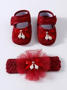 Detailaufnahme von roten Baby-Spitzenschuhen und passendem Stirnband mit Perlen