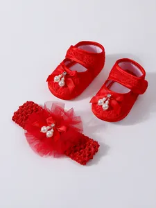 Detaillierte Ansicht von roten Baby-Spitzenschuhen und passendem Blumen-Stirnband-Set