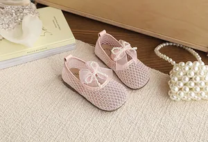 Close-up of pink mesh girl's sandals with elegant pearl bow detail.