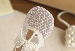 Close-up of elegant pearl bow and rhinestone mesh detail on girl's princess shoe