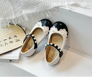 Detailansicht der schwarz-weißen Mädchenschuhe mit Spitze und Perlenverzierung