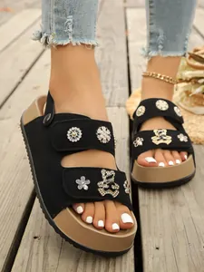 Detailaufnahme schwarzer Plateau-Sandalen für Damen mit Strass-Bär- und Blumenanhängern