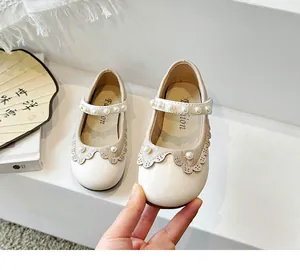 Nahaufnahme von cremefarbenen Prinzessinnenschuhen für Mädchen mit Perlenriemen