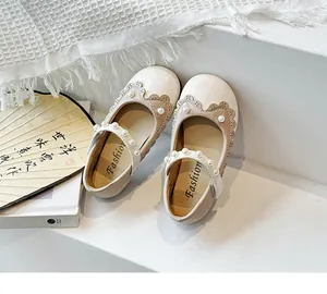 Detailansicht cremefarbener Kinder-Mary Janes mit Perlenriemen und gewelltem Rand