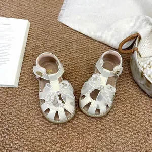 Vue rapprochée de sandales blanches pour filles avec nœud en perles et résille