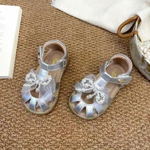 Vue détaillée de sandales argentées pour filles avec nœud en résille et perles élégantes.