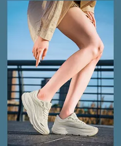 Close-up side view of breathable cream running shoes worn by a model in outdoor sunlight