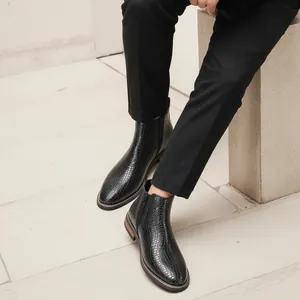 Gros plan sur des bottines Chelsea noires pour hommes avec texture crocodile raffinée.