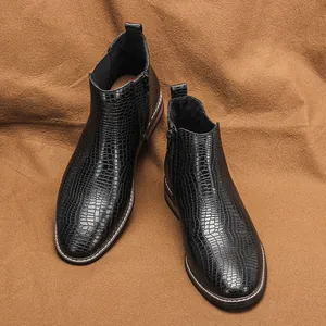 Vue détaillée des bottines Chelsea noires à motif crocodile sur tissu marron