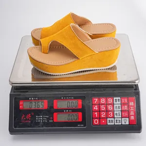 Gelbe Keil-Zehentrenner-Sandalen auf einer Digitalwaage mit Anzeige von null drei sechs fünf kg