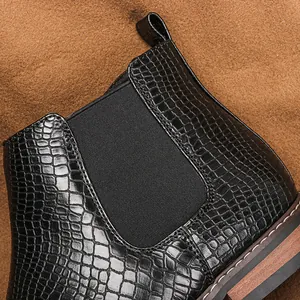 Gros plan sur la texture du cuir à motif crocodile noir d'une bottine Chelsea pour homme