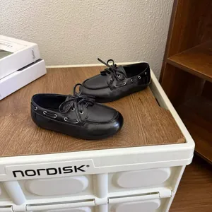 Gros plan de mocassins noirs pour enfants de style anglais avec lacets sur surface boisée