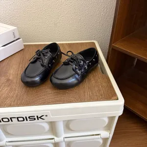 Vue détaillée de chaussures en cuir noires pour enfants de style anglais sur bois