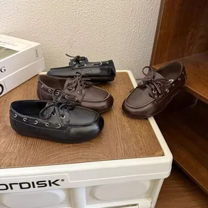 Vue détaillée de chaussures bateau classiques en cuir marron et noir pour enfants.