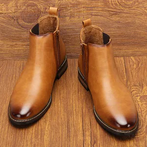 Bottines Chelsea classiques en cuir marron pour hommes avec zip sur sol en bois