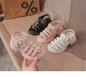 Gros plan de sandales romaines pour filles avec fleurs, en rose, noir et blanc cassé