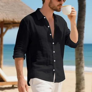 Dettaglio di una camicia in lino nero a maniche lunghe sulla spiaggia, vestibilità relax.