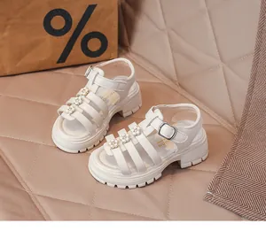 Gros plan de sandales romaines blanches pour filles avec détails floraux et semelle crantée.