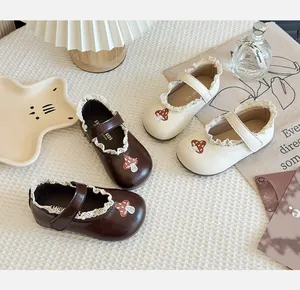 Detailed view of girls' cream and brown leather Mary Jane shoes with cute mushroom patches