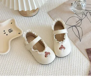 Close-up of girl's cream leather shoes with lace trim and mushroom embroidery