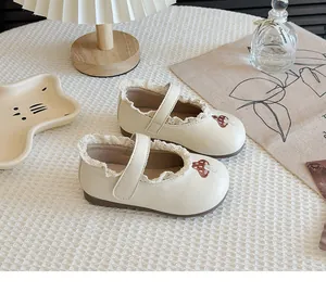 Detail of cream girls' Mary Janes featuring mushroom embroidery and delicate lace trim.