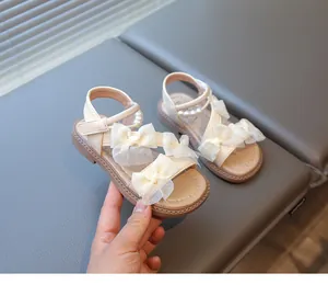 Close-up detail of elegant girl's fairy style princess sandals featuring lace bows and pearls