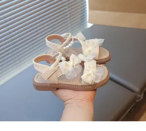 Beige girls' princess sandals with tulle bows and pearl details held by hand