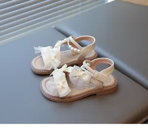 Detail view of girls' cream princess sandals with tulle bows and pearl strap accents