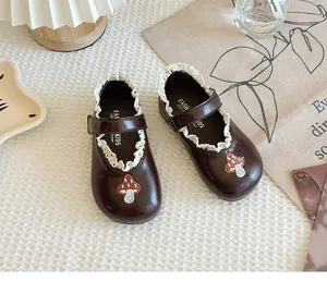 Detailed view of girls' brown leather Mary Jane shoes with cute mushroom embroidery and lace trim