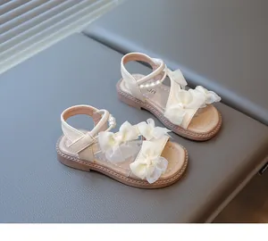 Close-up of girls' cream sandals featuring white organza bows and pearl ankle strap