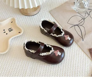 Close-up of brown girls Mary Jane shoes featuring delicate lace trim and mushroom embroidery