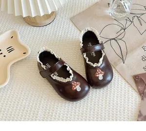 Detail shot of girls brown Mary Jane leather shoes with white lace and mushroom patch