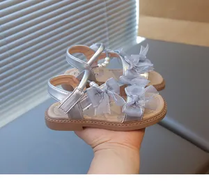 Close-up of girls silver princess sandals with ribbon bows and pearl details