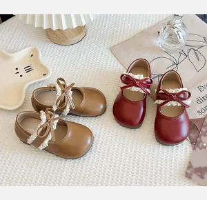 Detail der Mary-Jane-Schuhe für Mädchen mit Spitzendekor und Schleife in Braun und Rot